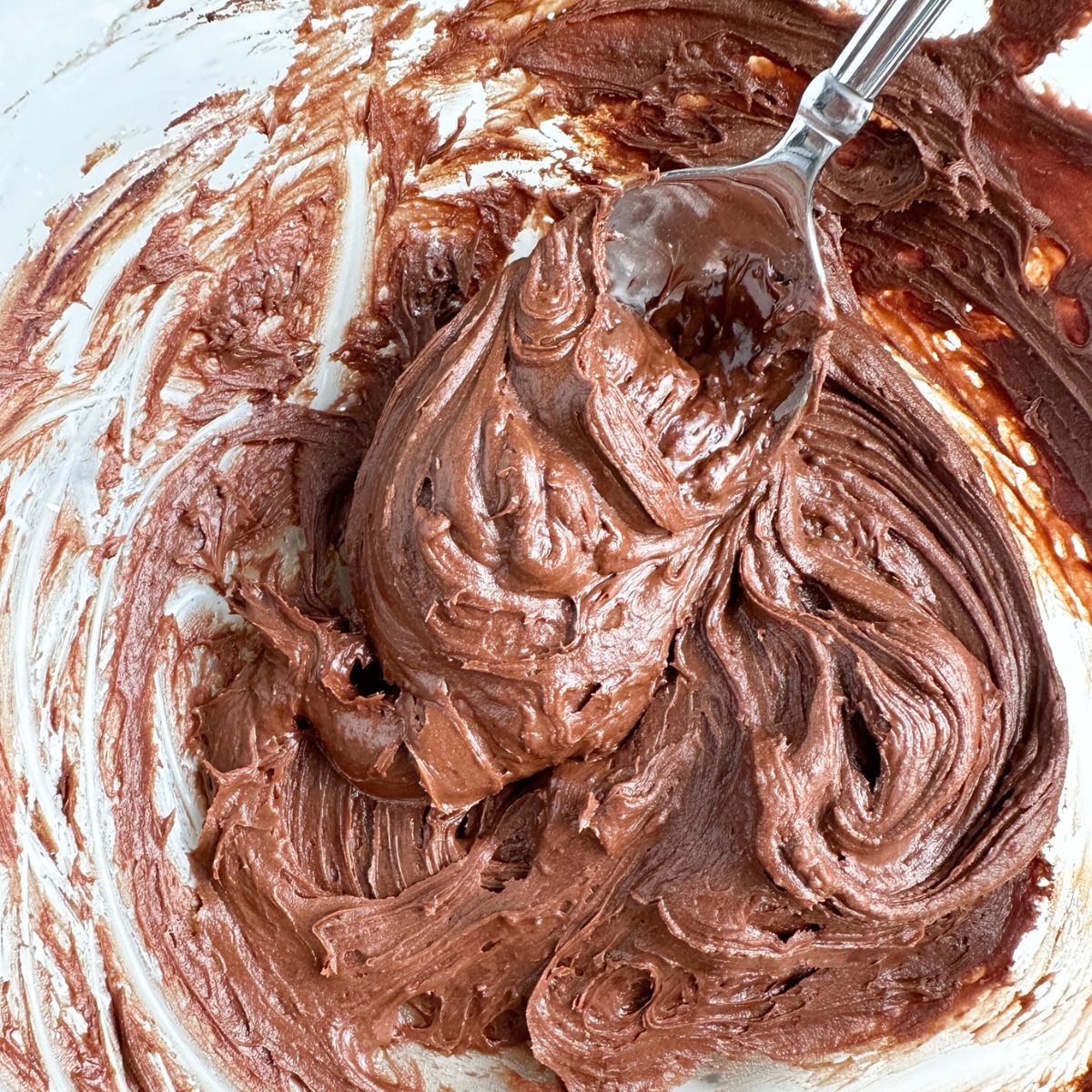 Bowl of chocolate frosting and spoon. 
