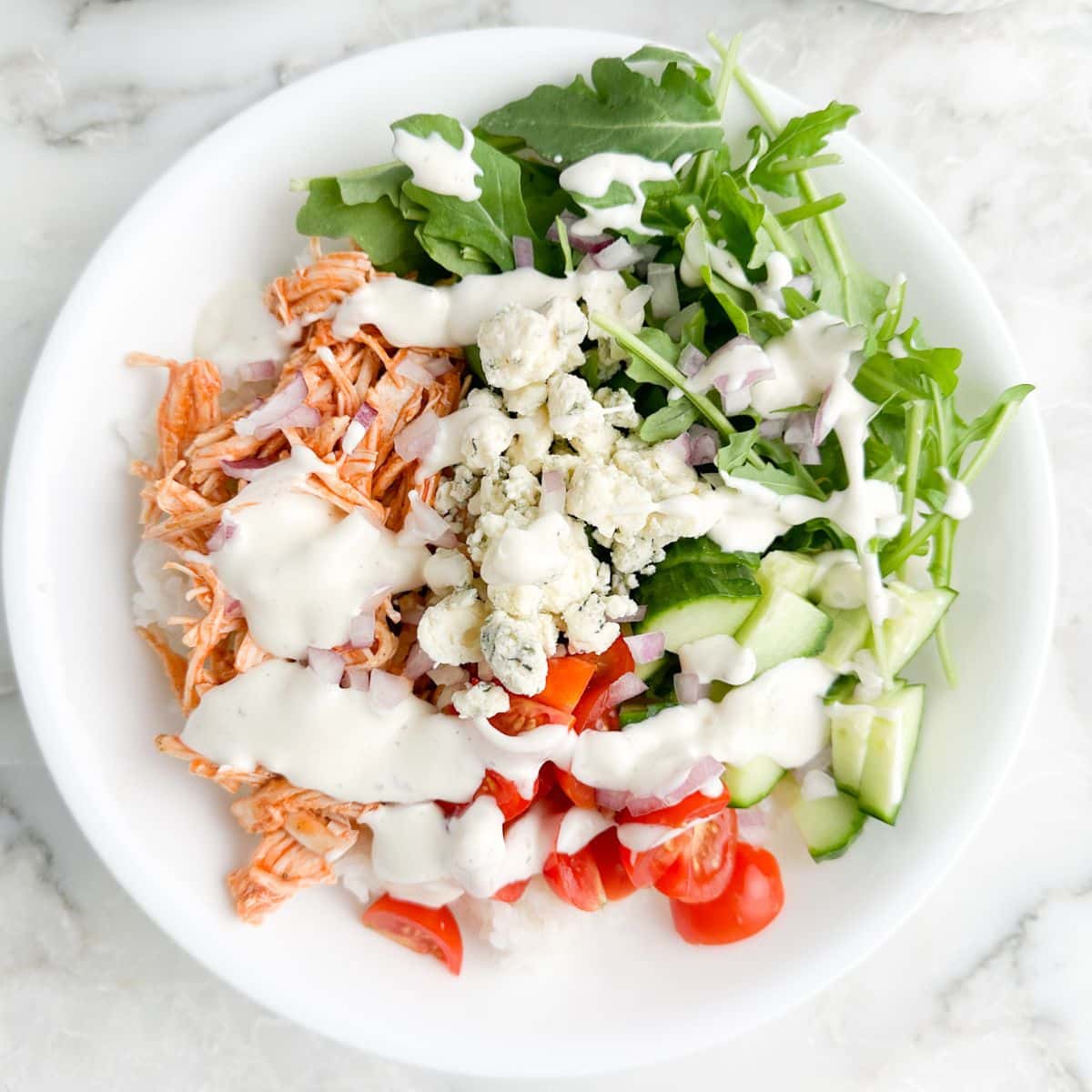 Bowl with shredded chicken, lettuce, rice, vegtables, and ranch. 