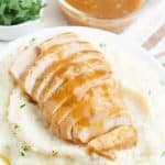 Sliced turkey tenderloin over mashed potatoes with gravy.