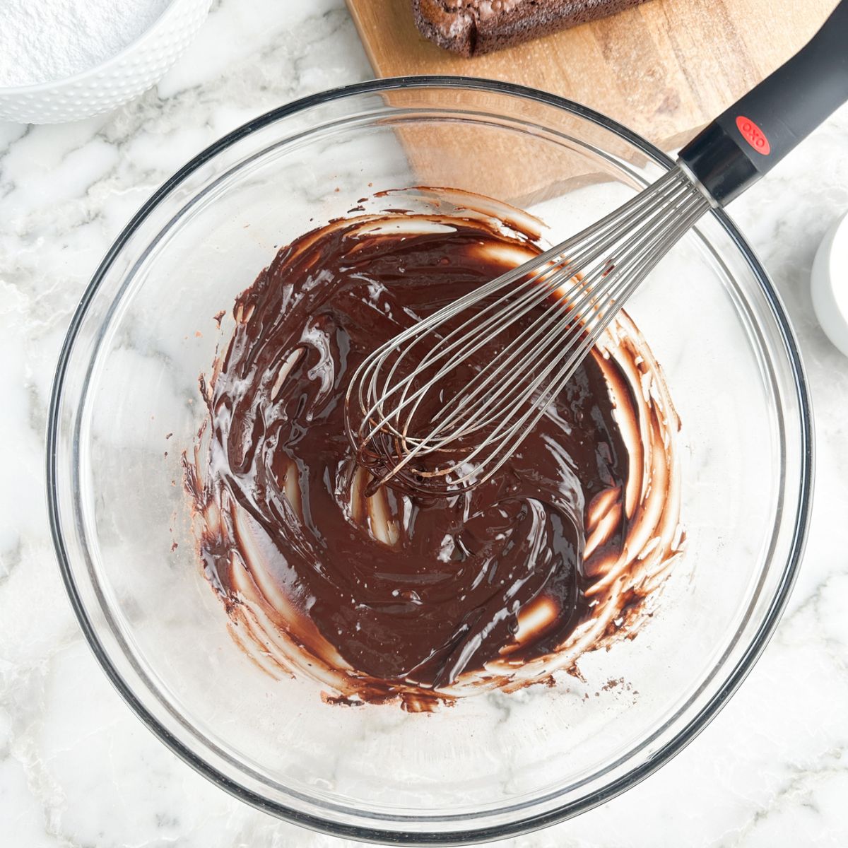 Bowl of cocoa powder and butter combined with a whisk. 