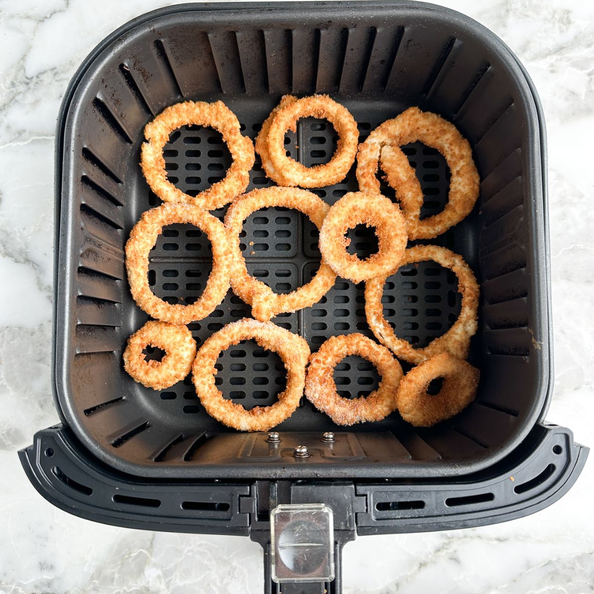 Onion rings in air fryer basket. 