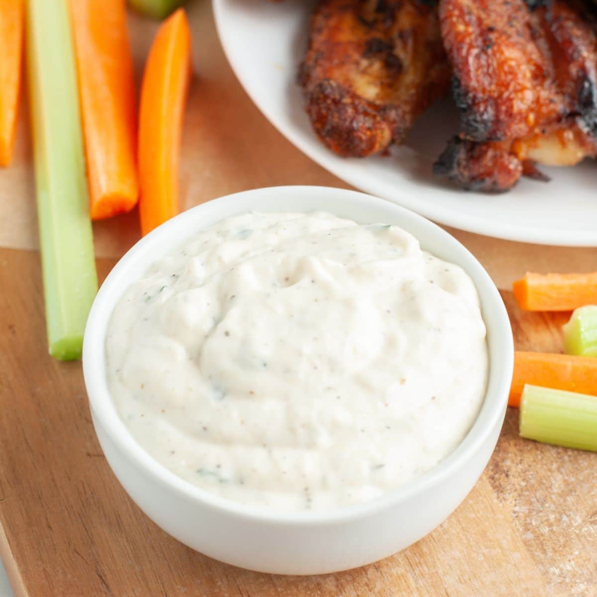 Bowl of creamy dip with chicken wings. 