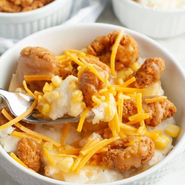 Bowl of fried chicken, mashed potatoes, and shredded cheese.