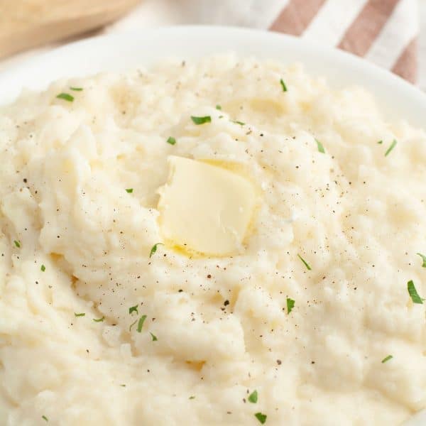 Bowl of mashed potatoes topped with butter.