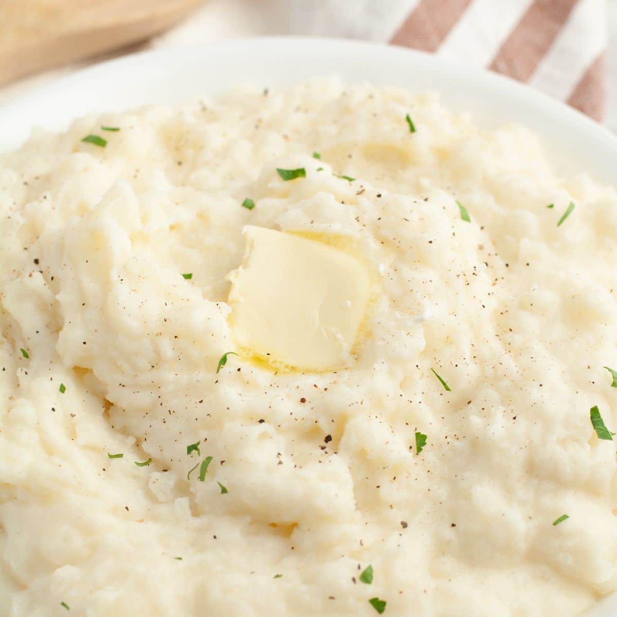 Bowl of mashed potatoes with pat of butter. 