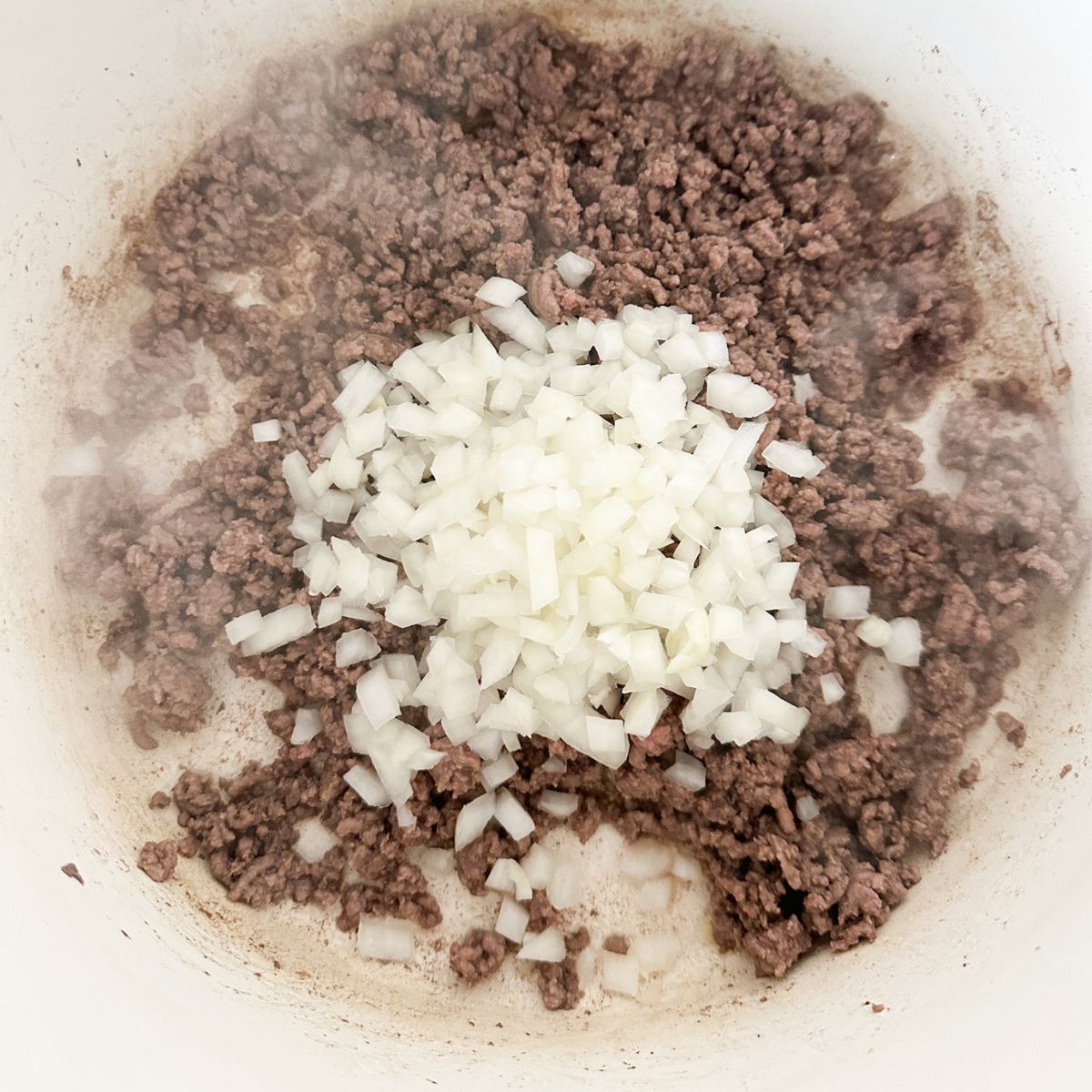 Ground beef and onion in a pot. 