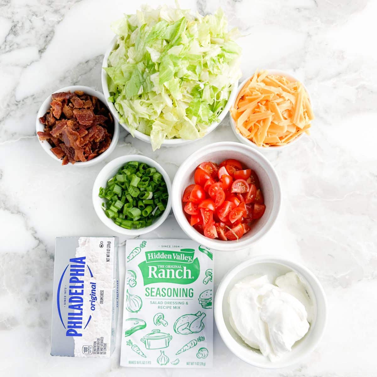 Bowl of lettuce, cheese, bacon crumbles, tomato, and sour cream. 