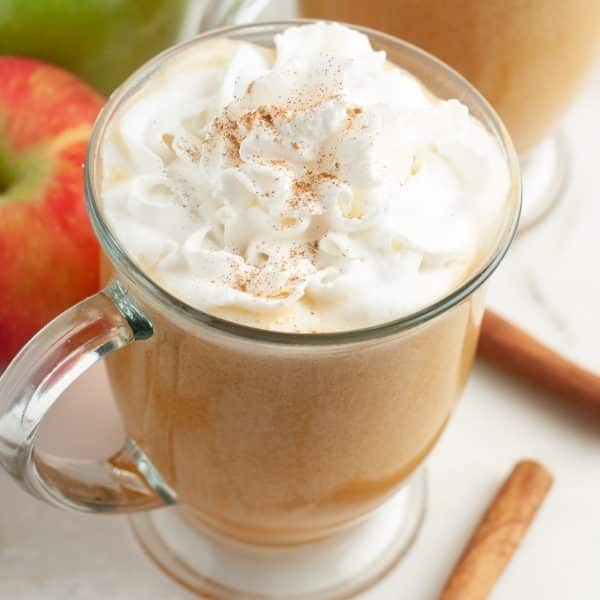Mug with apple cider and topped with whipped cream.