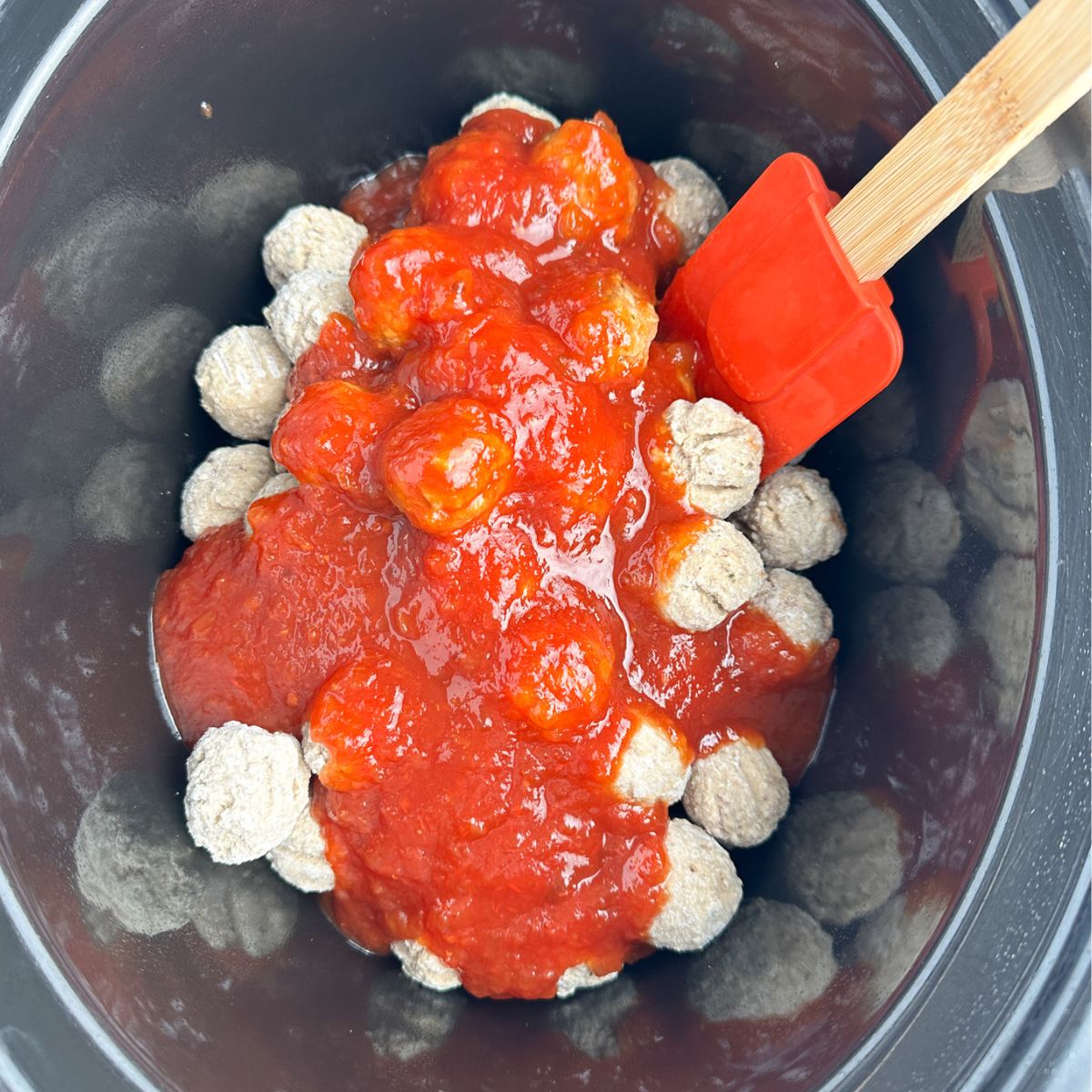 Frozen meatballs in slow cooker with sauce. 