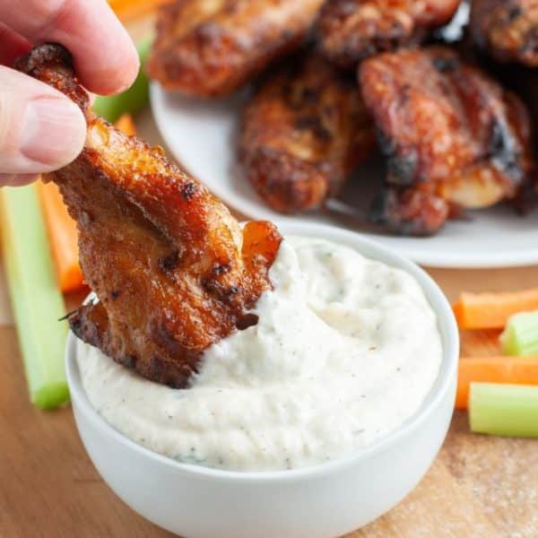 Wing dipping into creamy sauce.