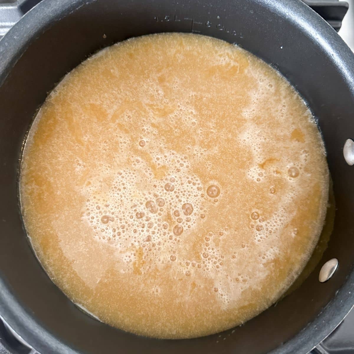 Saucepan with melted cream and brown sugar. 