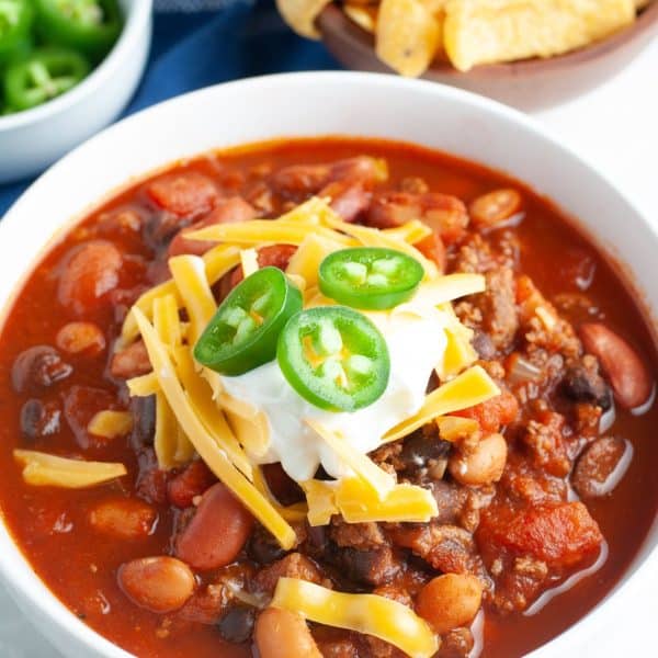 Bowl of bean chili topped with sour cream and jalapenos.