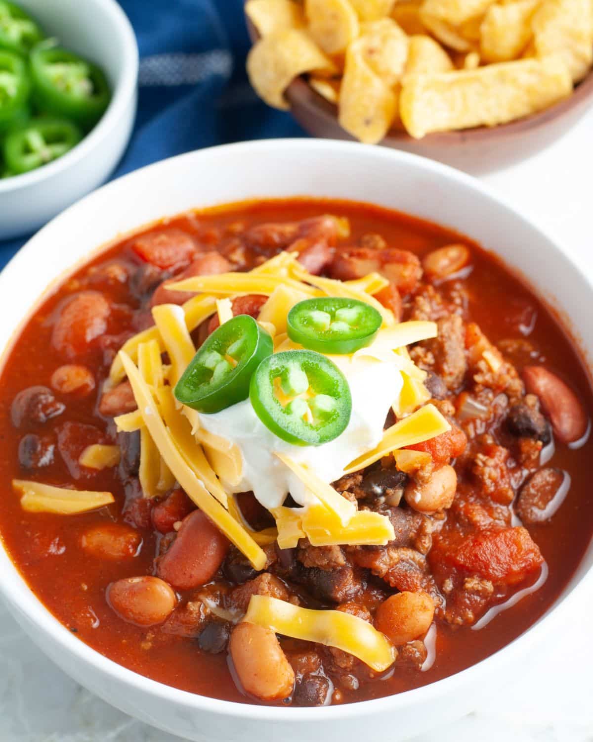 Bowl of bean chili topped with sour cream and jalapenos. 