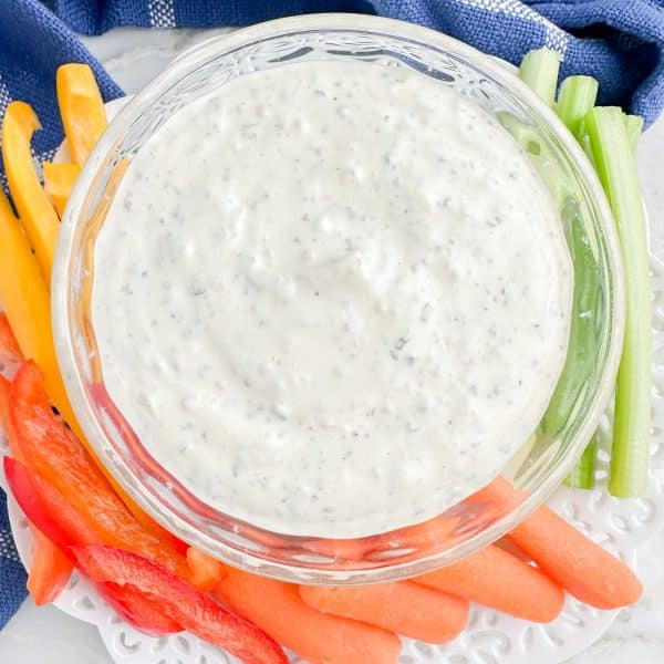 Bowl of creamy dip with cut vegetables.
