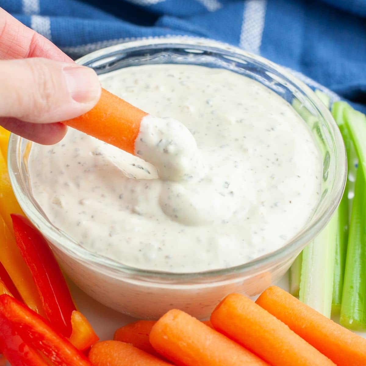 Carrot dipping into a bowl of creamy dip. 