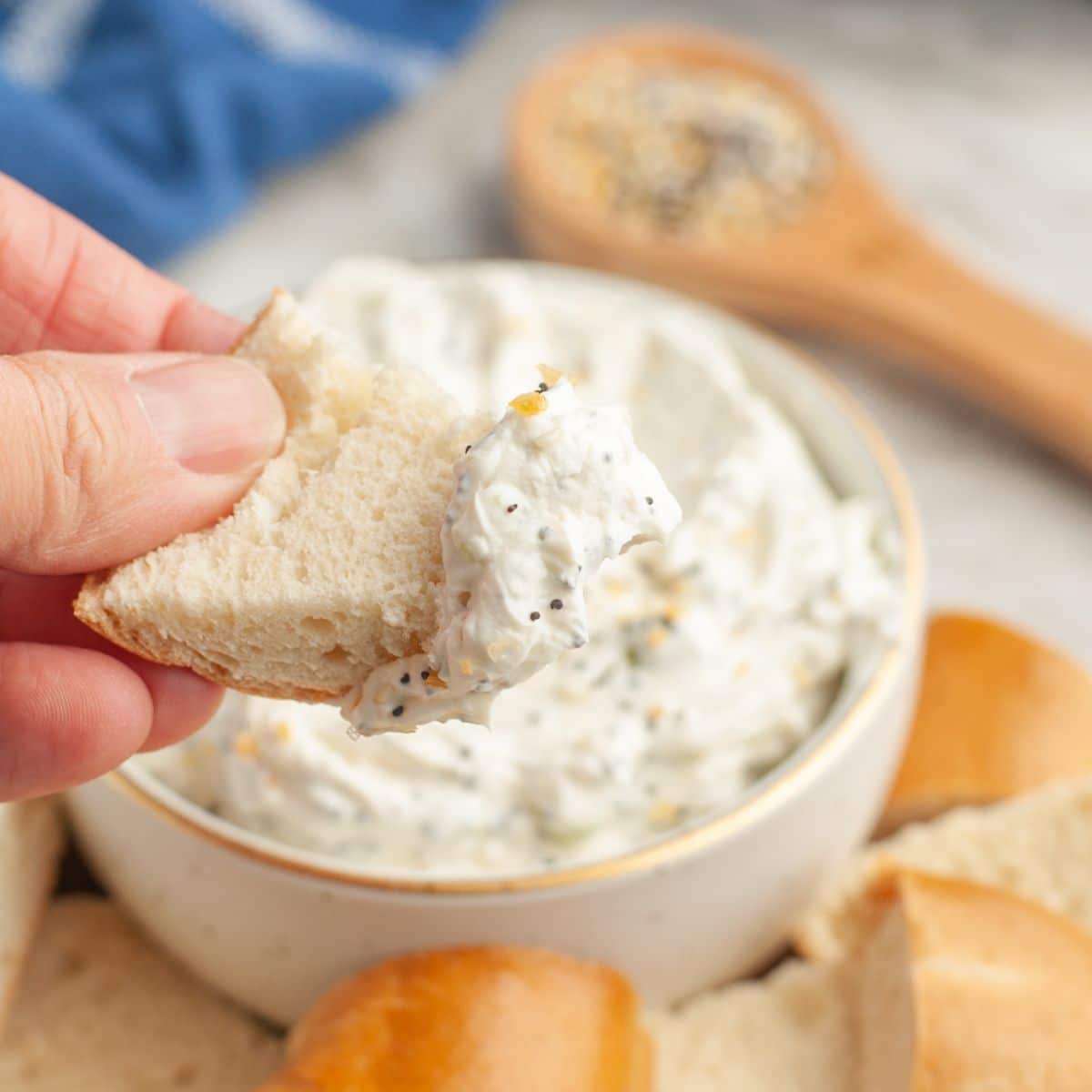 Bowl with bagel being dipped into cream cheese dip. 