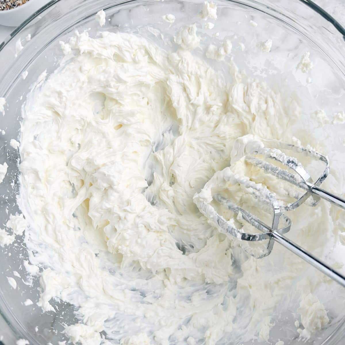 Whipped cream cheese in a bowl with a mixer. 