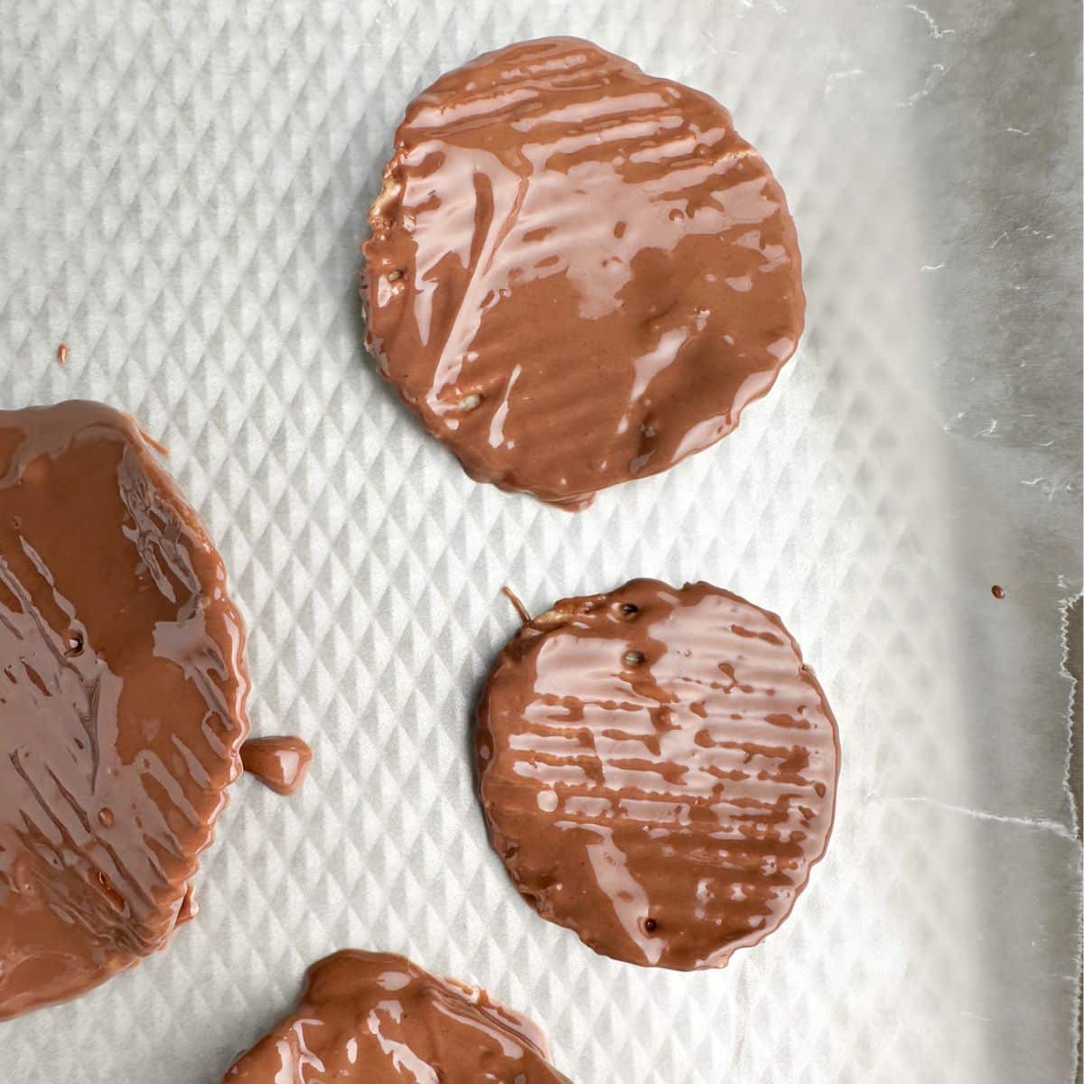 Chocolate covered potato chips on a baking sheet.