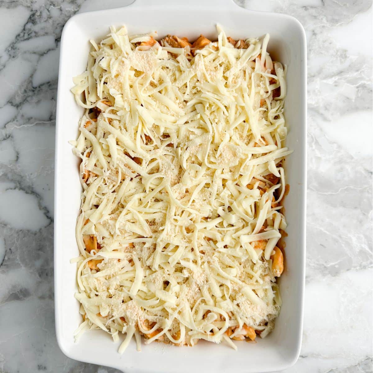 Shredded cheese on casserole in a baking dish.