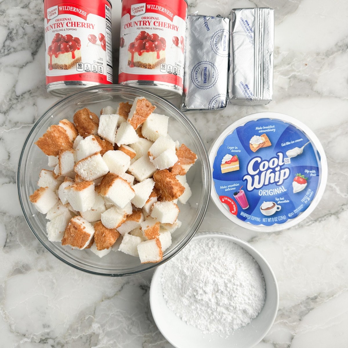 Cans of cherry pie filling, cubed angel food cake, cream cheese, powdered sugar, and cool whip.