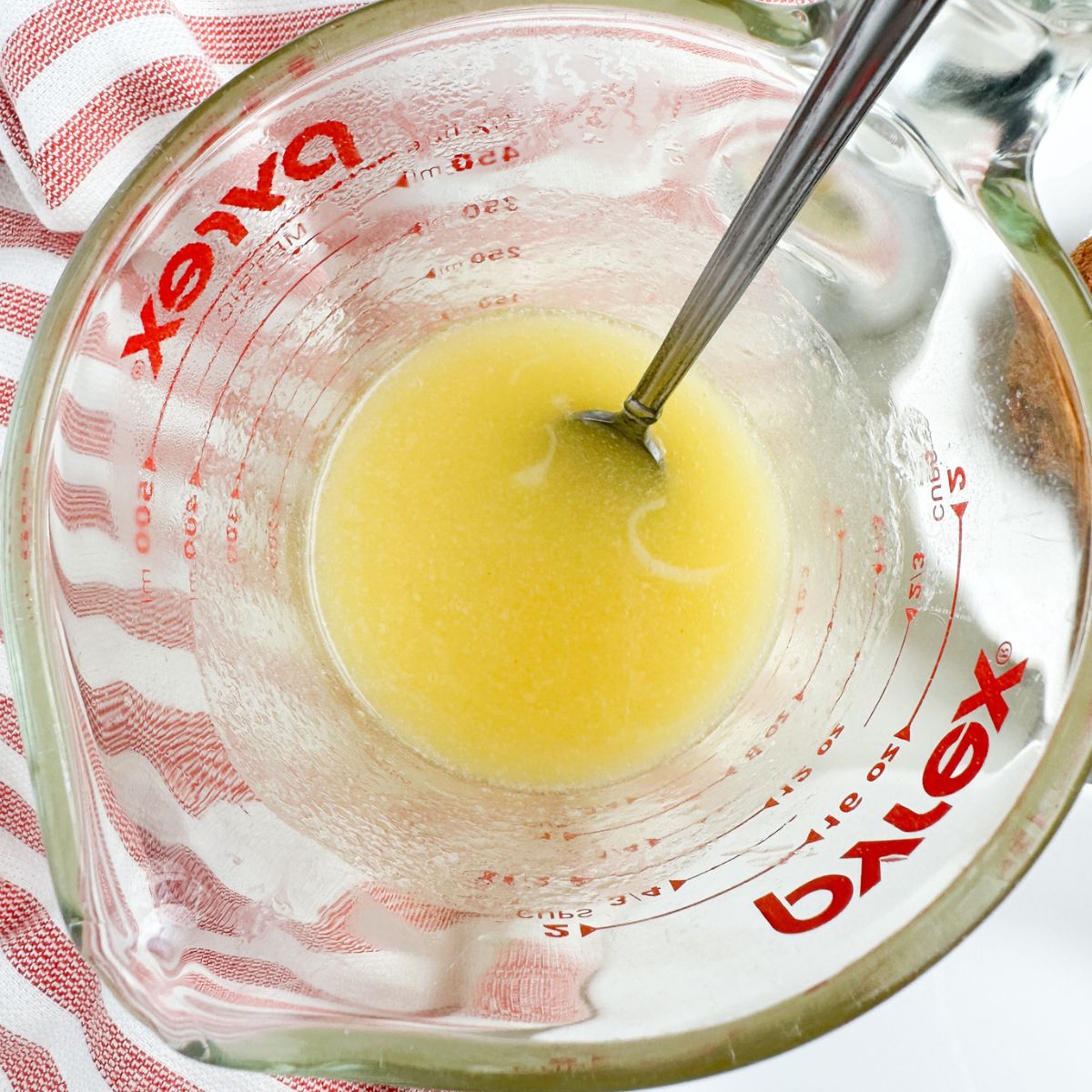 Glass bowl with melted butter and spoon.