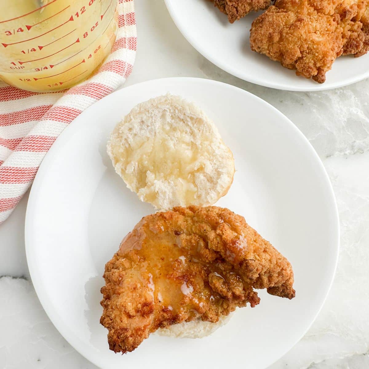 Biscuit topped with a chicken tender and honey.