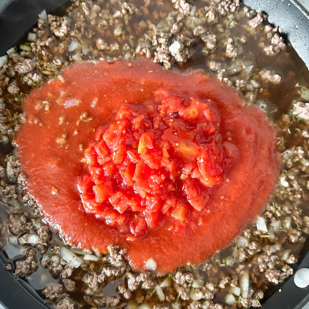 Skillet with ground beef and tomato sauce.