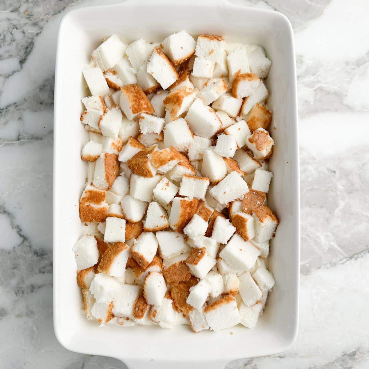 Casserole dish with cubed angel food cake.