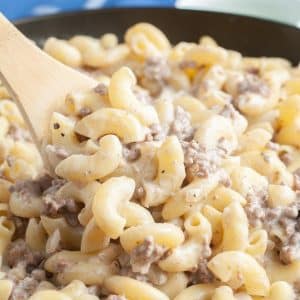 Wooden spoon with macaroni noodles and ground beef.