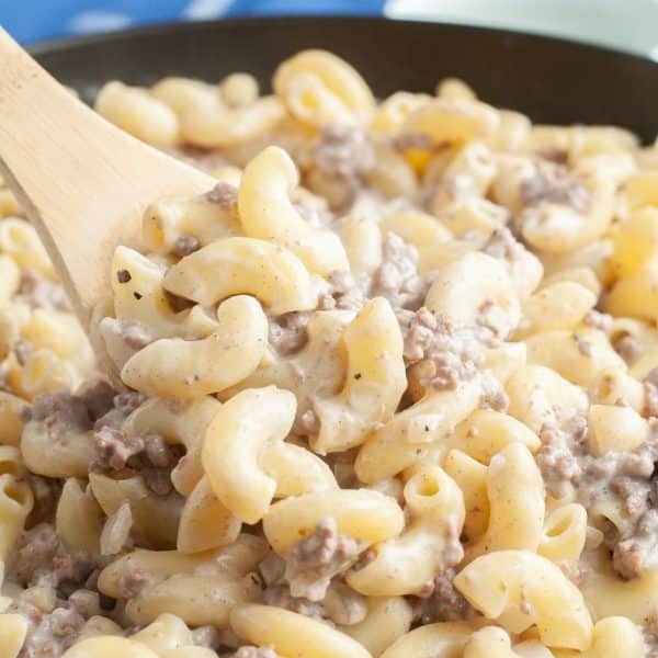 Wooden spoon with macaroni noodles and ground beef.