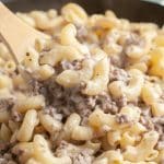 Wooden spoon with macaroni noodles and ground beef.