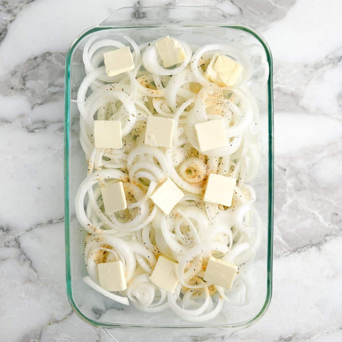Baking dish with sliced onions and butter. 