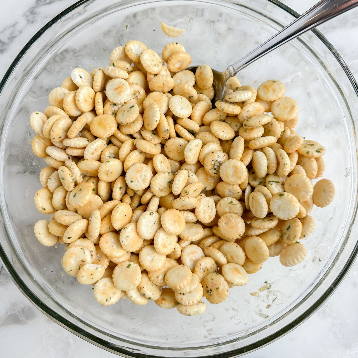 Oyster crackers in a glass bowl with a spoon.