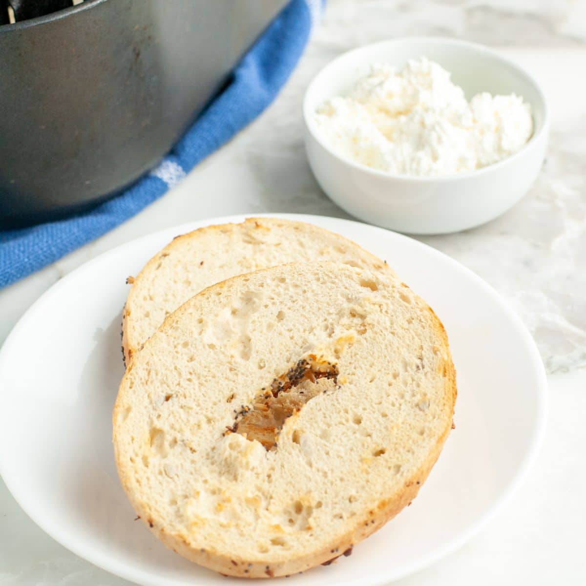 Toasted bagel on a plate with a bowl of cream cheese.