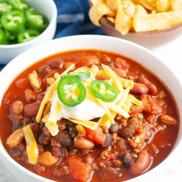 Bowl of chili with beans, sour cream and sliced jalapenos.