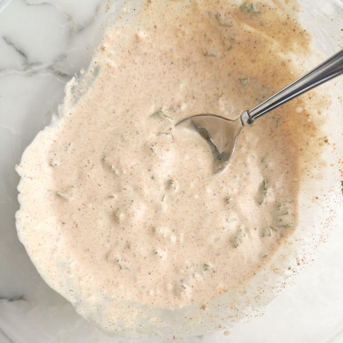 Bowl with mayonnaise based sauce and a spoon.