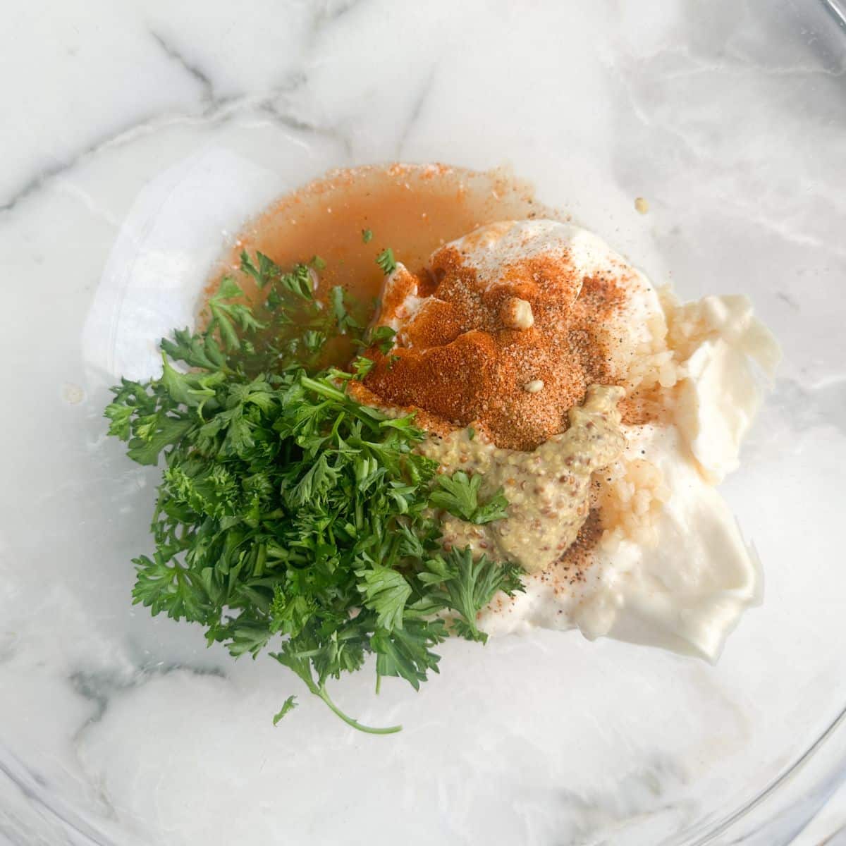 Bowl with mayonnaise, seasonings, and fresh parsley.