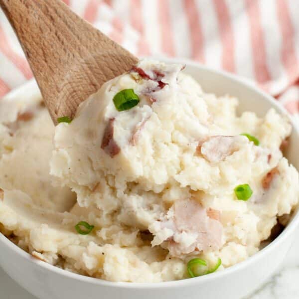 Bowl of mashed potatoes with a wooden spoon.