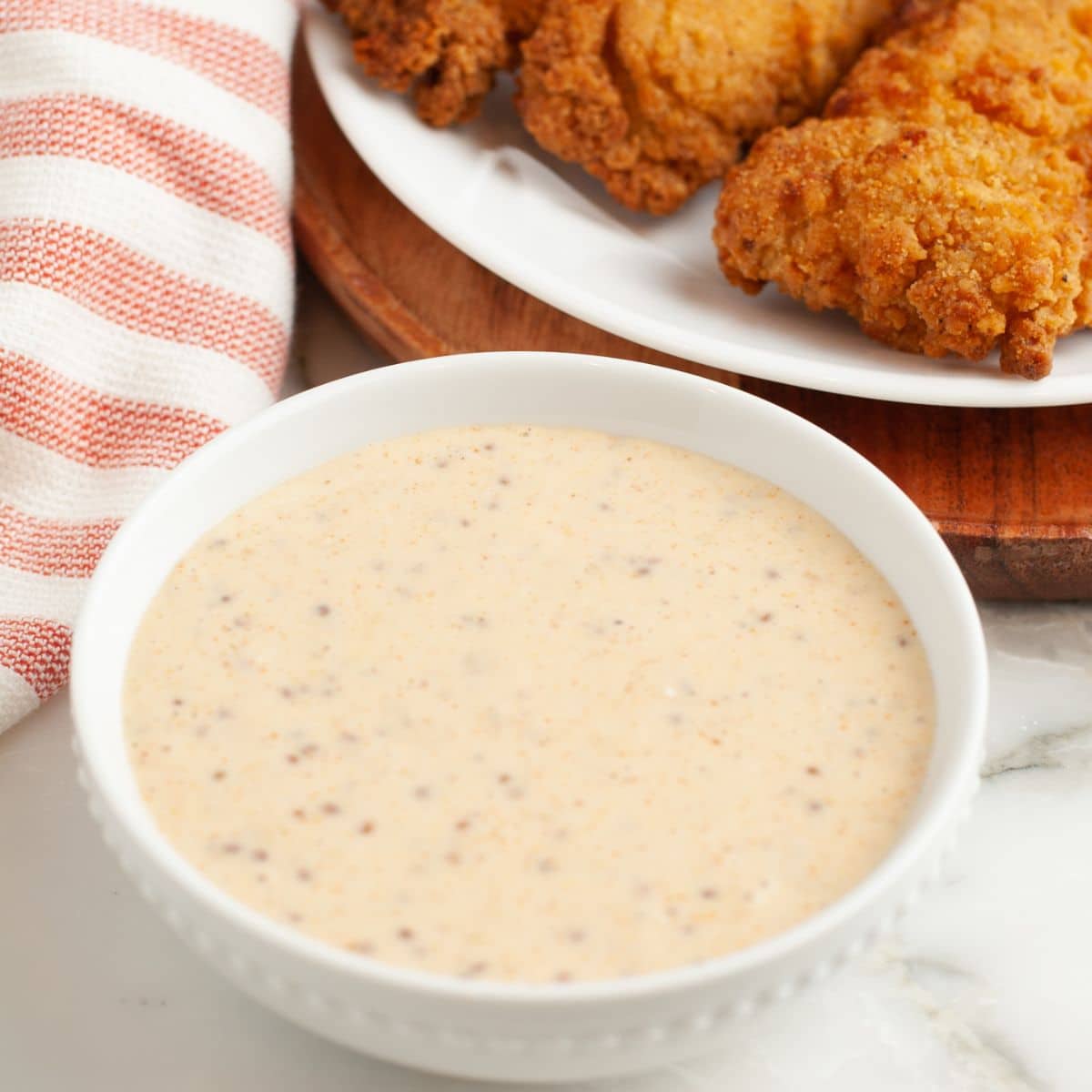 Bowl of creamy sauce with chicken tenders. 