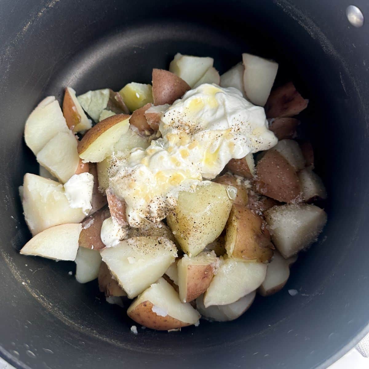 Pot with cubed potatoes, sour cream, and garlic. 