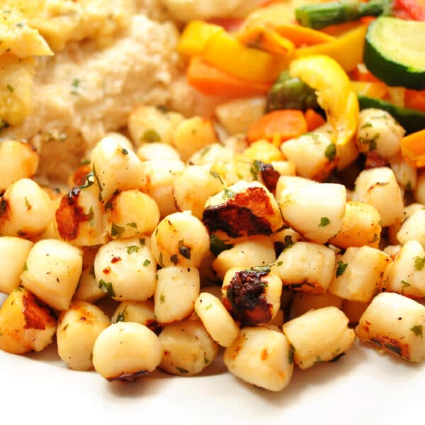 Plate of cooked bay scallops and vegetables.