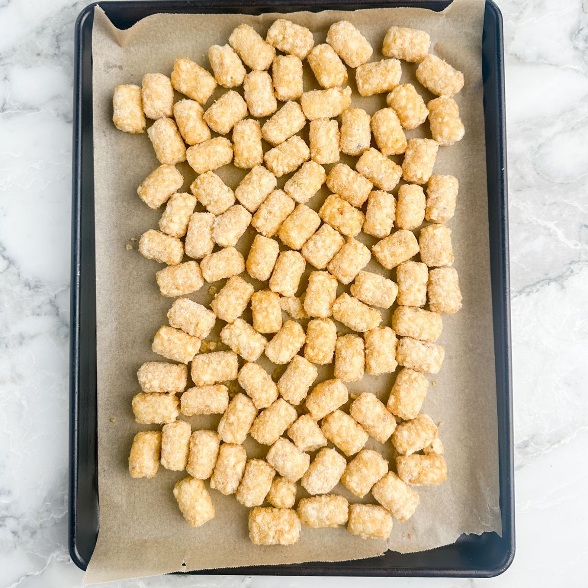 Baking sheet with frozen tater tots. 