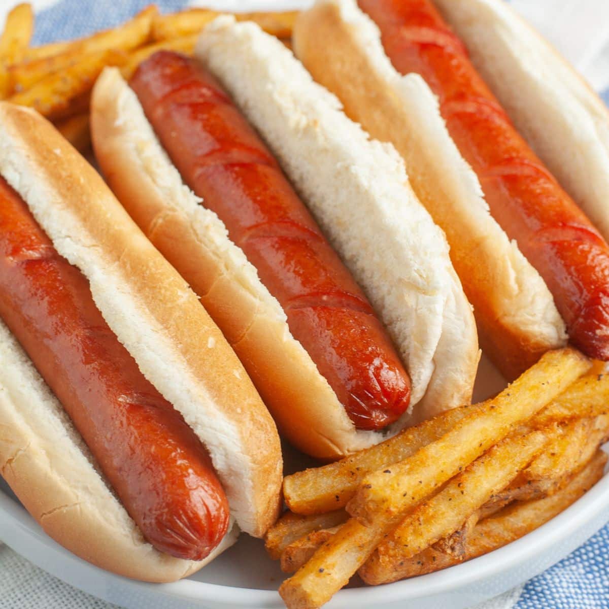 Hot dogs on a plate with french fries.
