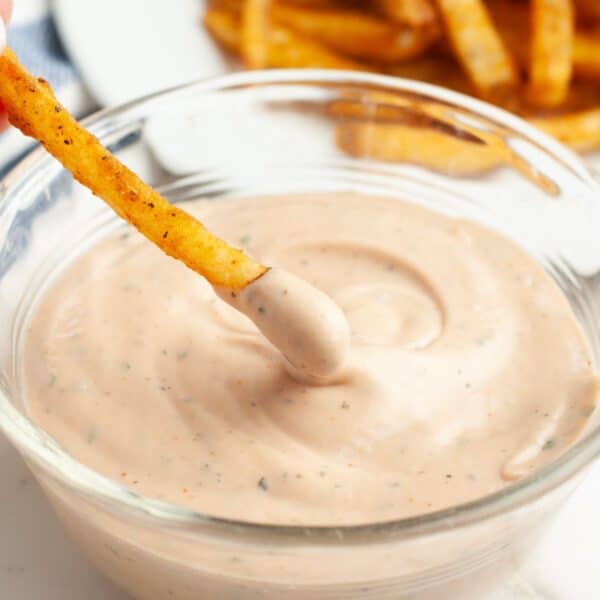 Bowl of BBQ ranch with a french fry dipping in.