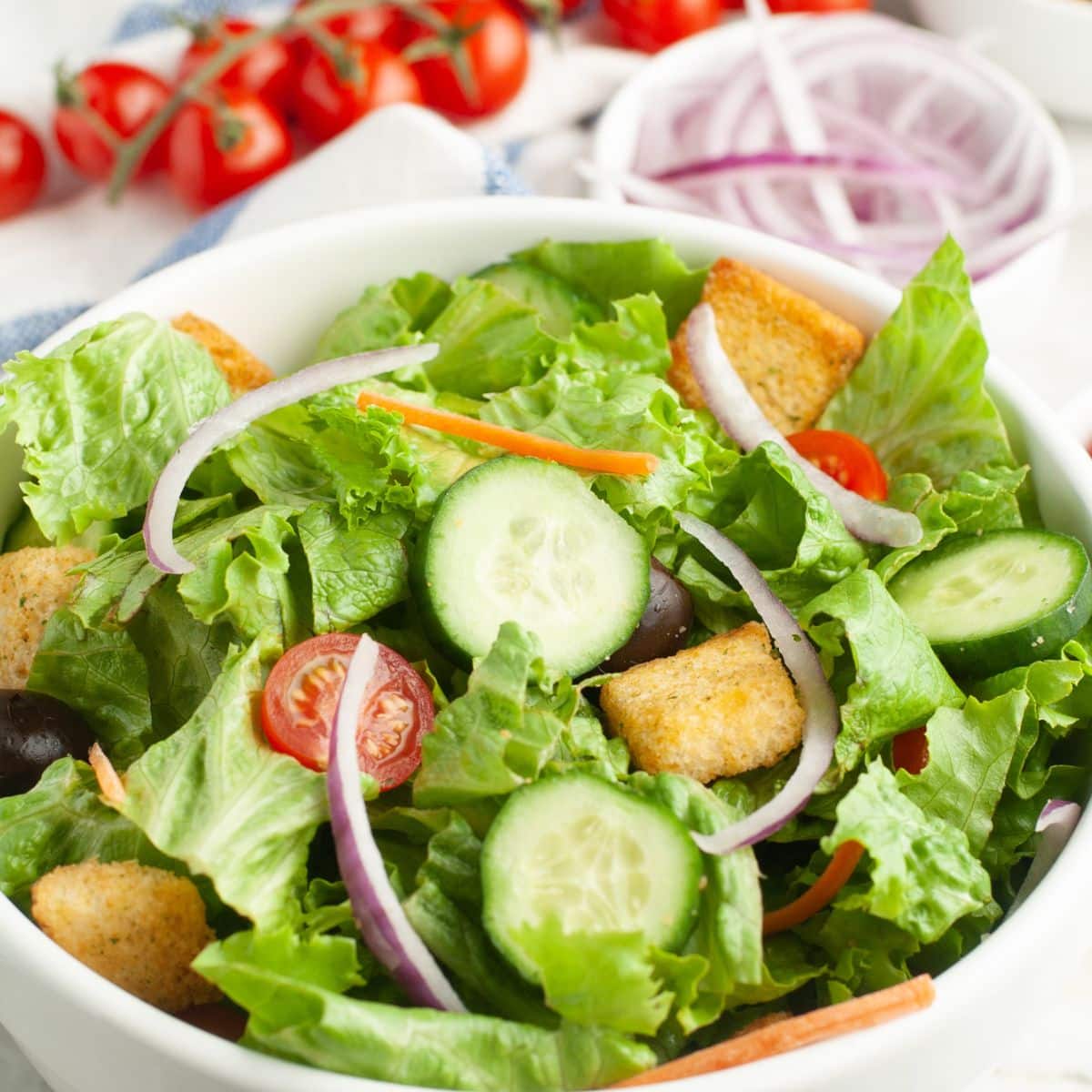 Bowl of lettuce, cucumbers, tomatoes, and onions.