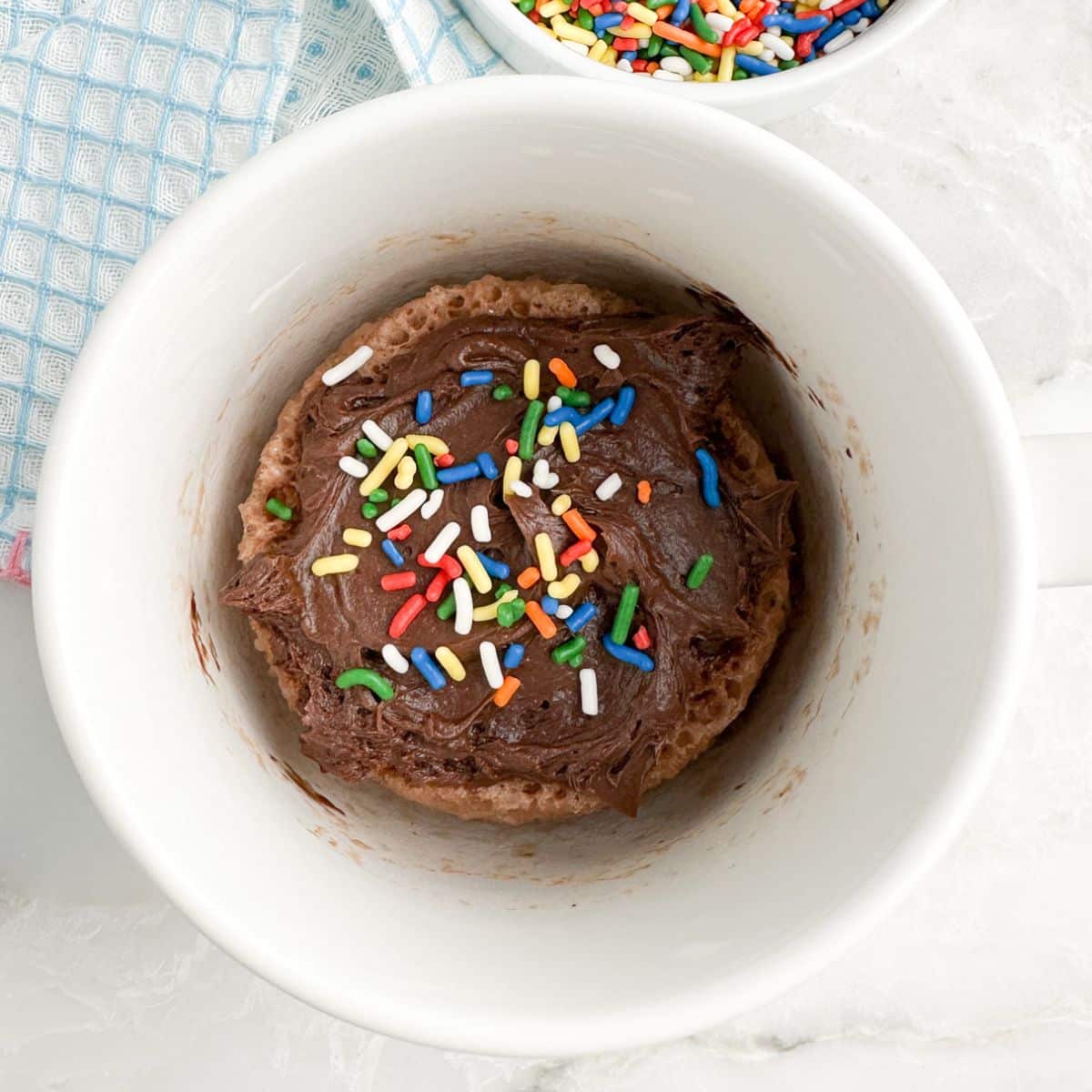 Mug with a chocolate cake and chocolate frosting inside.