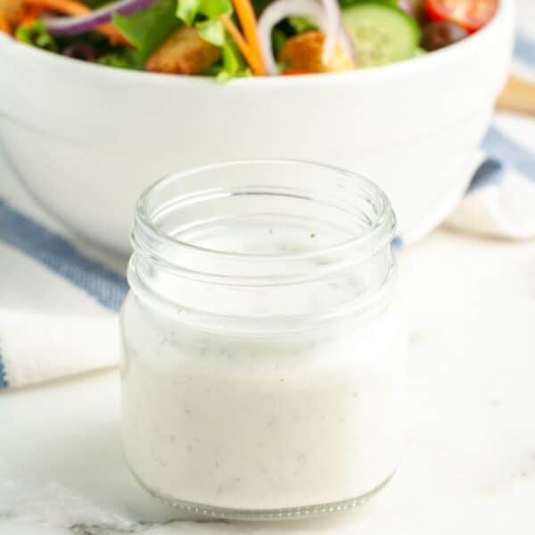Jar of creamy salad dressing and bowl of salad.