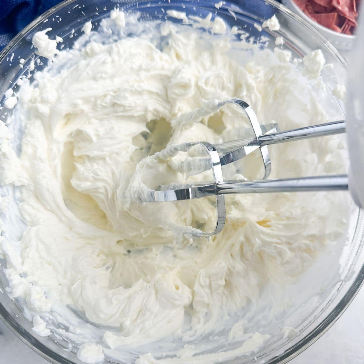 Bowl with mixer and cream cheese.