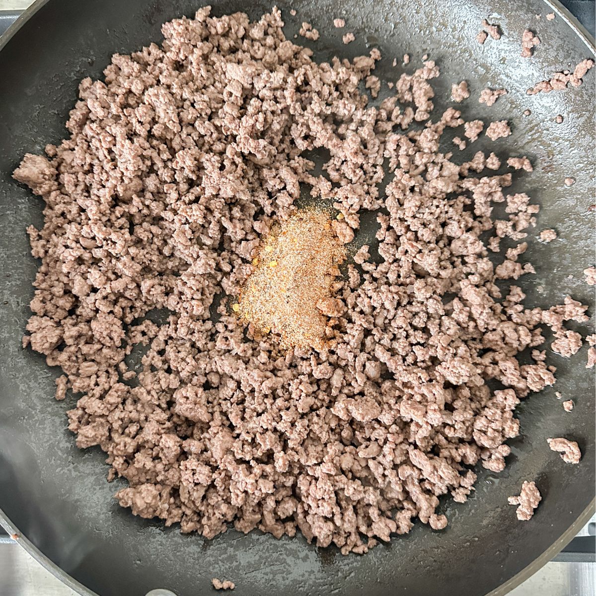 Ground beef with seasonings in a skillet. 