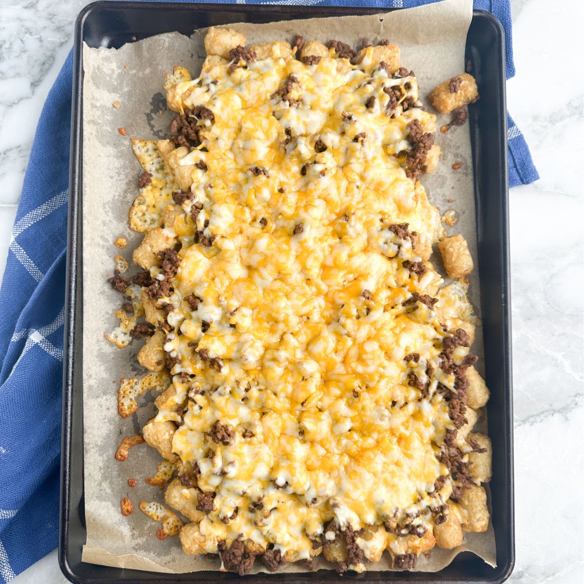Baking sheet with tater tots, ground beef, and melted cheese. 